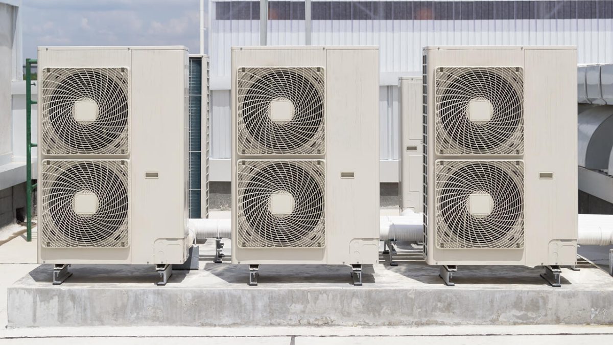 Row of commercial air conditioning condenser units on a rooftop plinth